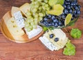 Blue and white grapes against different cheese on rustic table Royalty Free Stock Photo