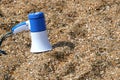 A blue-and-white horn speaker sits on the sand on the beach. Copy space