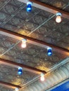 Blue and white light bulbs on pressed tin ceiling of city building