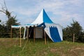 Blue and white medieval tent standing on the hill top with blue sky and white clouds Royalty Free Stock Photo