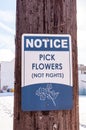 A blue and white metal sign that says pick flowers not fights on a telephone pole Royalty Free Stock Photo