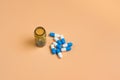 Blue and white pills in the brown glass bottle on a orange background
