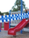 Blue and white Police tape cordoning off an colorful playground area like a crime scene