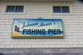 A blue and white sign on the side of a white building that reads Johnnie Mercer\'s Fishing Pier in Wrightsville Beach