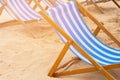 Blue and white striped deckchairs standing on sand on a beach