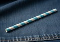 A blue and white striped paper straw rests on a dark blue denim fabric Royalty Free Stock Photo