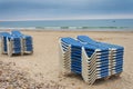 Blue and white striped sunbeds stacked on the beach on a cloudy summer afternoon Royalty Free Stock Photo