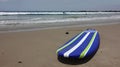 Blue and white striped surfboard on beach