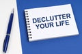 On a blue-white surface lies a pen and a notebook with the inscription - Declutter Your Life Royalty Free Stock Photo