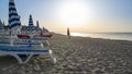 Blue and white umbrella and deckchairs at the beach in front of adriatic sea at sunrise. Calabria, Simeri Mare, Italy