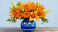 a blue and white vase filled with orange flowers on top of a wooden table next to a blue and white wall and a blue wall Royalty Free Stock Photo