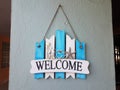 Blue and white welcome sign with shells on wall