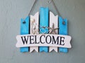 Blue and white welcome sign with shells on wall