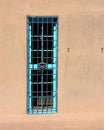 Blue window with bars on an adobe wall Royalty Free Stock Photo