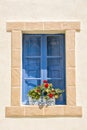 Blue window with brick frame with red flowers in the Maltese alleys Royalty Free Stock Photo