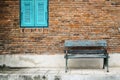 Blue window, rustic bench chair by brick wall exterior