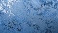 Blue winter background or wallpaper. Drawing of ice crystals and frost on the window glass in winter. A pattern of leaves of Royalty Free Stock Photo