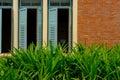 blue wood louver window & orange brick wall near garden