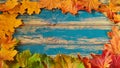 Blue wooden autumn background with free copy space for text. Round fall frame of yellow, green and red maple leaves Royalty Free Stock Photo