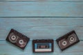 On a blue wooden background at the bottom of the frame are three audio cassettes. There is a place for the text on the top