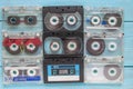 On a blue wooden background, old scratched audio cassettes lie in three rows