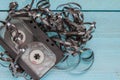 On a blue wooden background, there is an audio cassette with an unwound magnetic tape