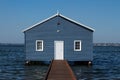 Blue wooden boatshed surrounded by water against clear blue sky Royalty Free Stock Photo