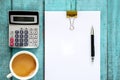 Blue wooden desk table with paper ream, pen, calculator and cup