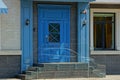 Blue wooden door and threshold on the wall of a building with a window Royalty Free Stock Photo