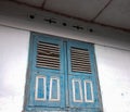 A blue wooden house window, ancient style, with white walls