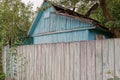 Blue wooden loft of a rural house with a small window behind a gray fence Royalty Free Stock Photo