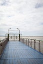 Blue wooden pier with railing on a river. Closed gates decorated with anchors