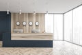 Blue and wooden reception desk with clocks and computers near window