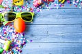 Blue wooden surface with party flappers, an egg and sunglasses on the sides Royalty Free Stock Photo