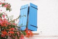 Blue wooden window shutter in house adorned with red flowers Royalty Free Stock Photo