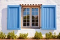 blue wooden window shutters on whitewashed spanish revival building