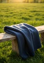 Blue Wool Blanket on Wooden Bench in Grassy Field at Sunset Royalty Free Stock Photo