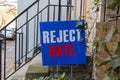 A blue yard sign that says Reject Hate is placed on the front yard of an old building Royalty Free Stock Photo