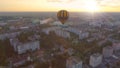 Blue-and-yellow air balloon flying over town at dawn towards sun, fantasies