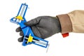 Blue and yellow angle clamp in worker hand in black protective glove and brown uniform isolated on white background