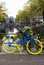 Blue and Yellow Bike Supporting Ukraine on a Bridge above a Canal during Autumn in Amsterdam