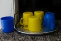 blue and yellow colored plastic cups on top of a metal tray