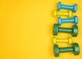 Blue, yellow and green dumbbells on yellow background