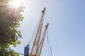 Blue and yellow harbour cranes on background of cloudless blue sky at daytime. Sand, cargo, freight