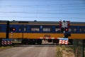 Blue yellow koploper intercity train at a railroad crossing in Moordrecht the Netherlands.