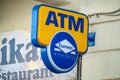 The blue and yellow logo of an ATM of the Euronet worldwide network of these machines in front of a local store