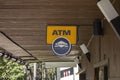 The blue and yellow logo of an ATM of Euronet worldwide network under the wooden roof of the store