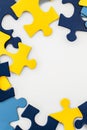 Blue, yellow, navy pieces of puzzle frame on white background. World autism awareness day concept. Top view, copy space Royalty Free Stock Photo