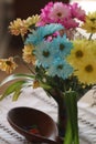 Blue, yellow, and pink daisy flowers in vase next to wood bowl of multicolored jelly beans on cream lace table runner Royalty Free Stock Photo