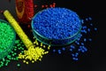 Blue, yellow, red granules of polypropylene, polyamide in a test tube and a petri dish. Black background. Plastic and polymer indu Royalty Free Stock Photo